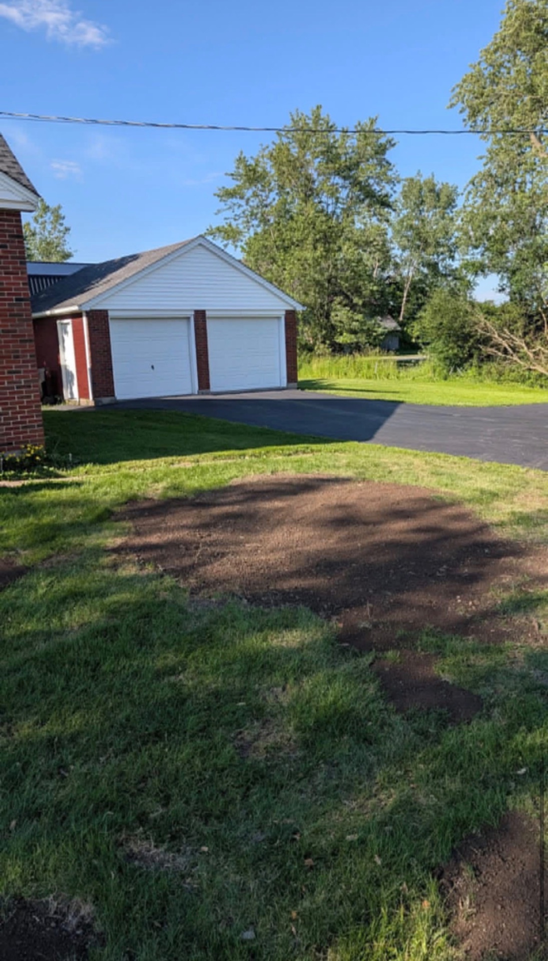 Yard area cleaned up and levelled after stump grinding beside a garage driveway